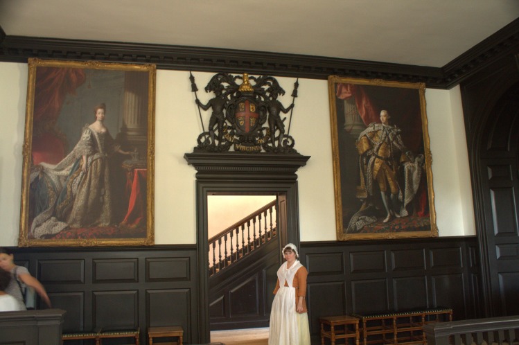 The interior of the Governor's Palace, with portraits of Queen Charlotte and King George III bordering the doorway.